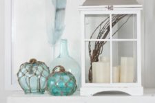 20 a beachy console with an oversized lantern with candles, floats, a feather artwork and a crate with books
