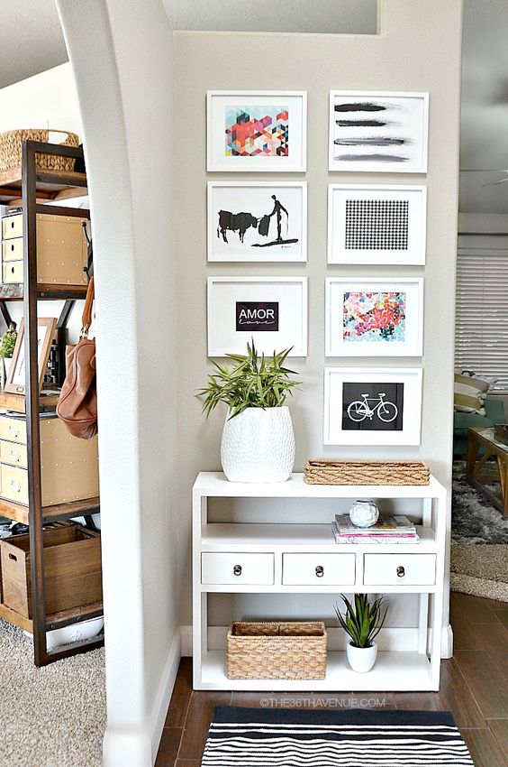 a small console with bold artworks over it, potted greenery and some baskets for storage