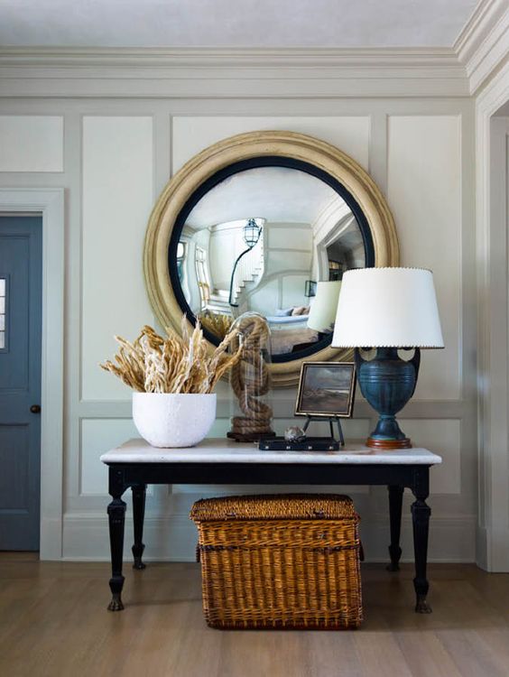 a nautical console with rope in a cloche, corals, a navy lamp and an artwork for a whimsy look