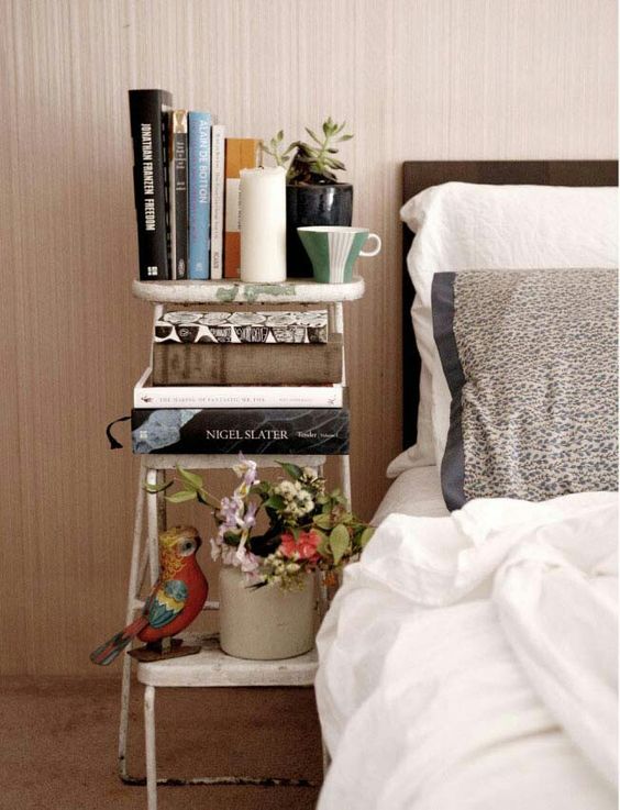 a small vintage ladder acts as a bedside bookshelf and doesn't cost a lot of money