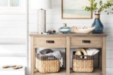 23 a rustic beachy console, baskets under it, a wooden bowl with shells and some colored glass plus an artwork