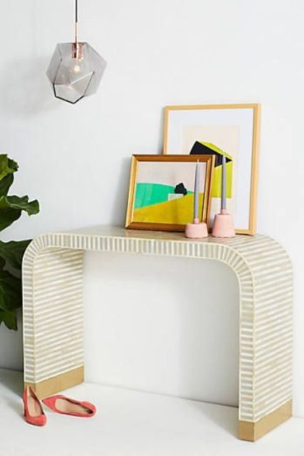 a waterfall inlay console, colorful artworks and candle holders for a mid-century modenr interior