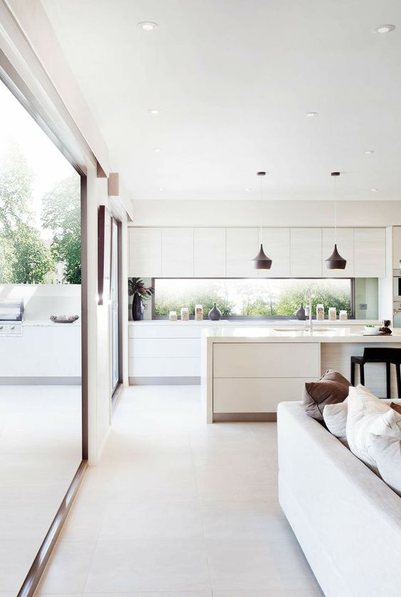a white contemporary kitchen with a window backsplash and glazed walls to tie the spaces