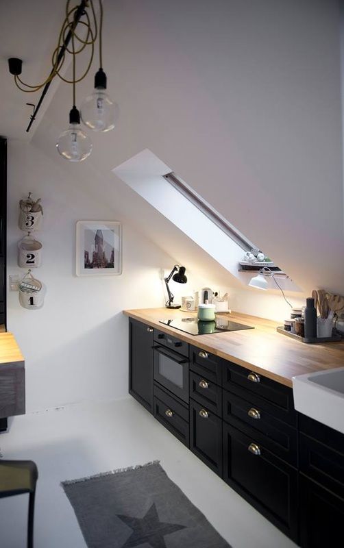 a Scandinavian attic kitchen with black cabinets, wooden countertops and skylights