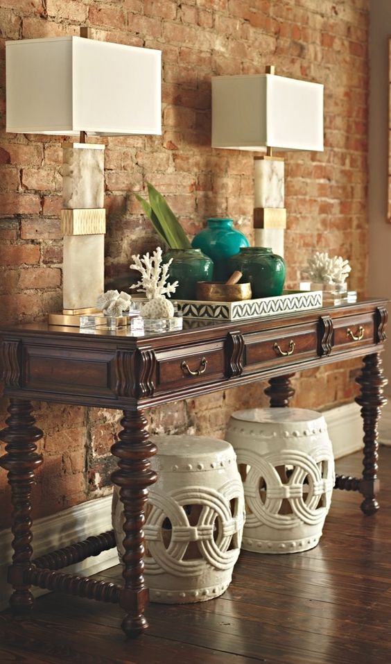 a vintage console table with corals, colored pots and vases and stone base lamps