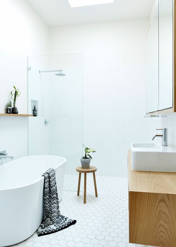 a white bathroom with a wooden vanity and stool for a textural touch