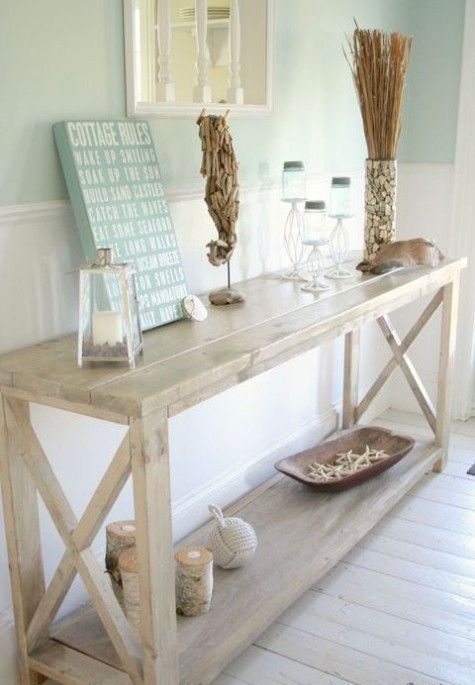 a whitewashed console table, candles in glass candle holders, starfish, a sea horse of driftwood and a shell clad vase