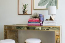 26 an encrusted console table, colorful books, tropical artworks over the table and hammered metal ottomans