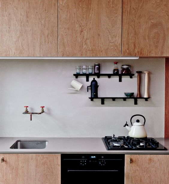 light-colored plywood cabinets and a blush plaster backsplash for a unique mid-century modern look