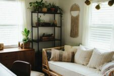 a small boho guest bedroom with a metal shelving unit, a stained dresser, a rattan bed with pillows, a desk and a chair, some boho decor