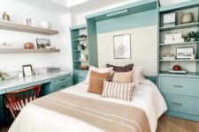 a welcoming guest bedroom with a mint blue storage unit and a Murphy’s bed, a matching desk, open shelves