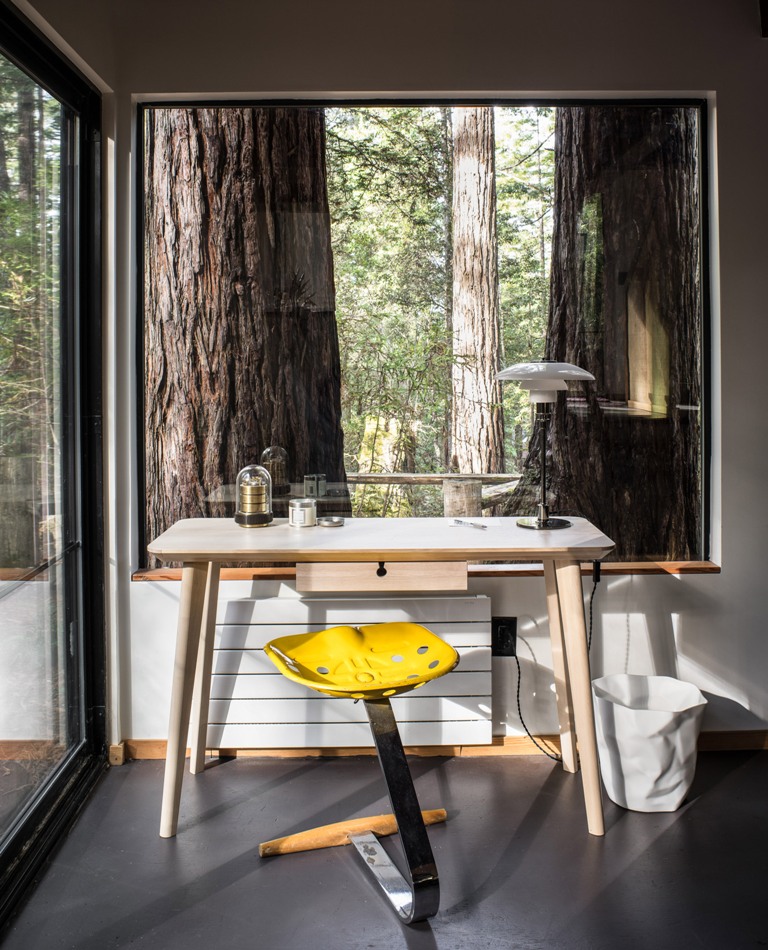 The home office features a mid-century modern desk and a bright stool, there are openings outside everywhere