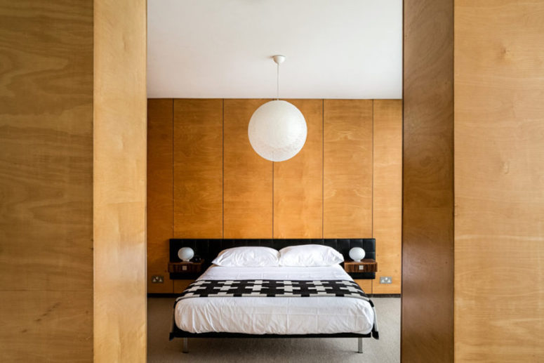 The master bedroom is clad with light-colored plywood, there's a comfy bed and a couple of wardrobes