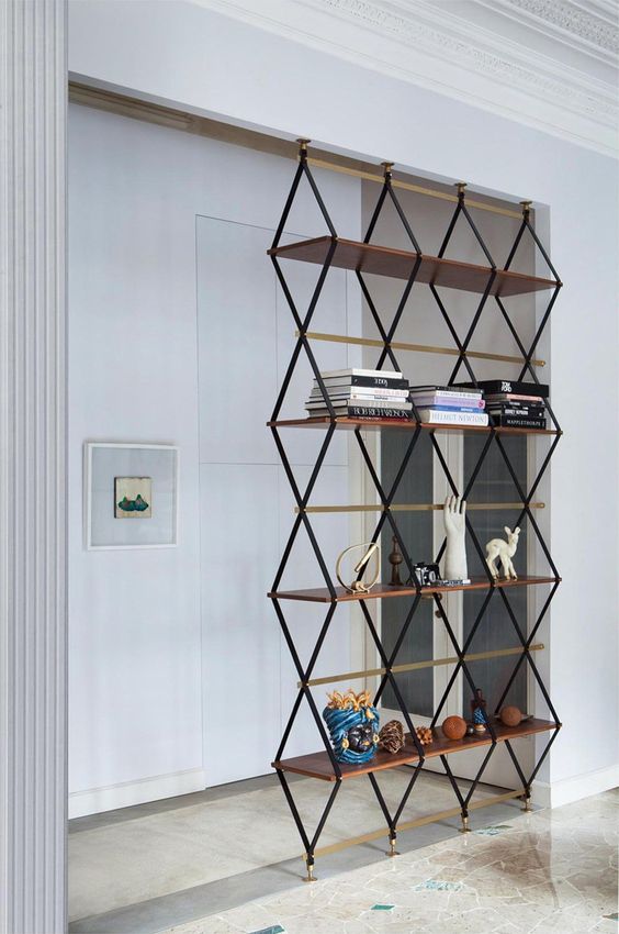 a floor to ceilinglightweight shelving unit separates the entryway from the living room