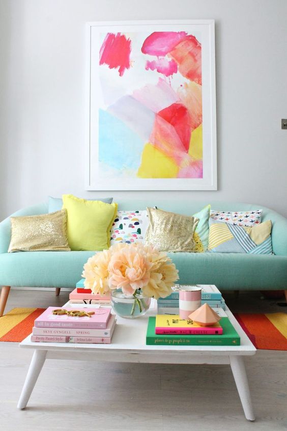 a mint sofa is a soft base for adding bright colors with the rug and the artwork for a cheerful feel