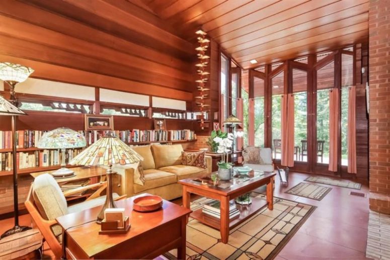 The living room features high ceilings, a glazed wall, lots of bookshelves and a selection of red wood furniture