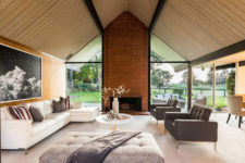 03 The living room is done with a glazed wall, a brick clad fireplace and a selection of comfortable and chic furniture