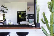 03 a black and white space with a dark stained bar counter and black metal stools plus cacti