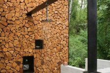 03 a contemporary rustic outdoor shower with a firewood wall and a dark metal panel