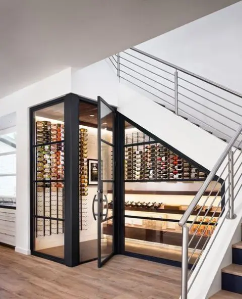 A cool modern under stairs wine cellar with lots of bottles on wall mounted shelves and additional lights