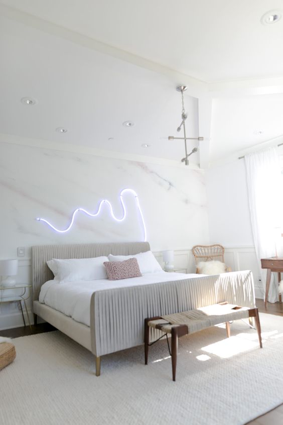 a neon light piece over the bed is a great idea to spruce up the space and make it modern and bold
