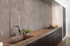 03 an industrial kitchen with dark metal cabinets and a concrete countertop plus a backsplash