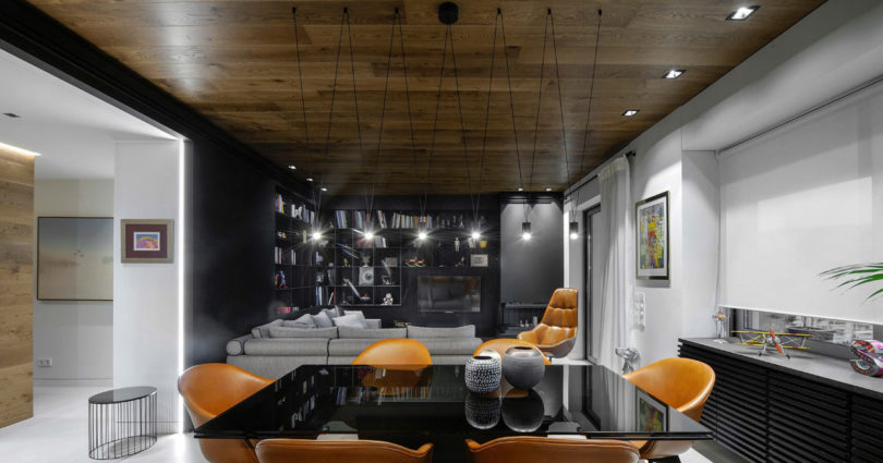 The dining space features a black table with a glass top and amber leather chairs