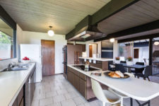 04 The kitchen features dark wooden cabinets, metal touches and white countertops
