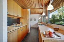 04 The kitchen is done with light-colored wooden cabinets, and there’s a breakfast zone further