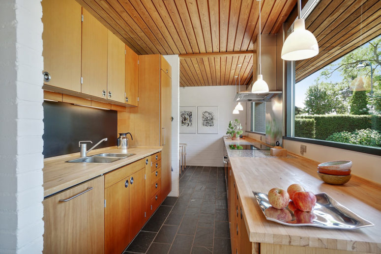 The kitchen is done with light-colored wooden cabinets, and there's a breakfast zone further