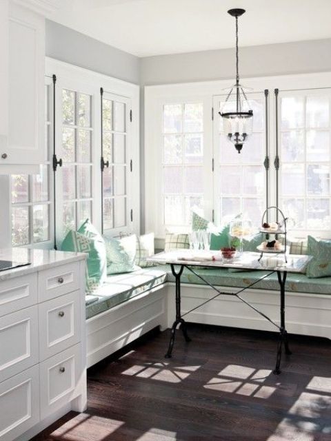 a coastal kitchen and dining space with a banquette seating in aqua shade