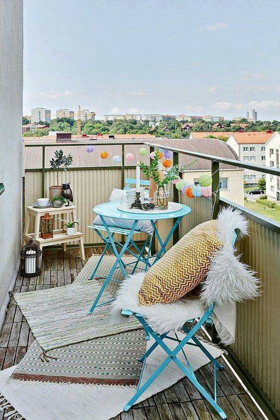 a colorful balcony with bright blue furniture, a ladder, candle lanterns and rugs