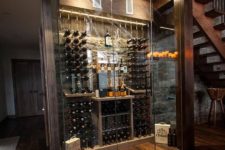04 a gorgeous glass-enclosed wine cellar under the stairs with additional lights and candles