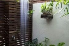 04 a gorgeous outdoor shower clad with dark stained wood and lots of potted plants plus a rain shower