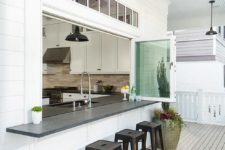 04 a kitchen pass through is fitted with glass folding windows fitted with a black bar lined with black stools