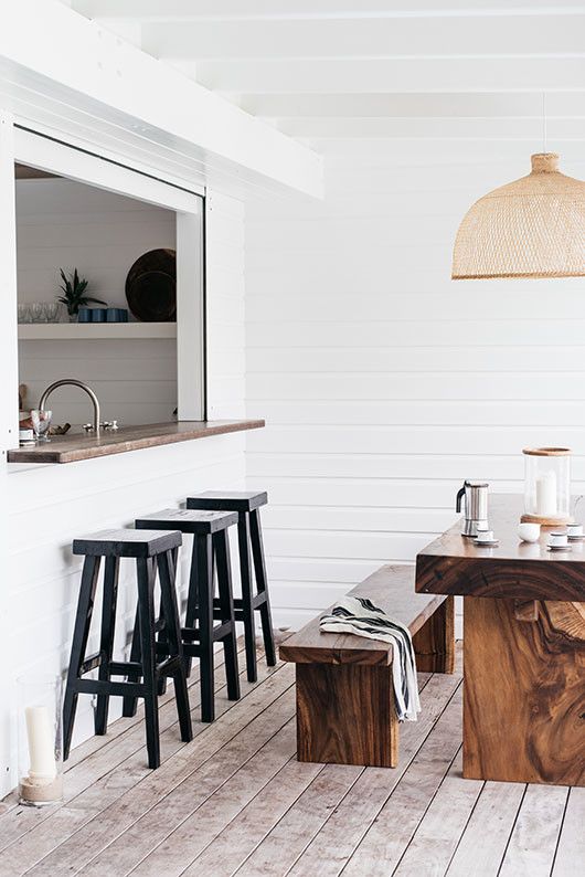 a minimalist space with a kitchen window, a concrete bar counter and tall black stools