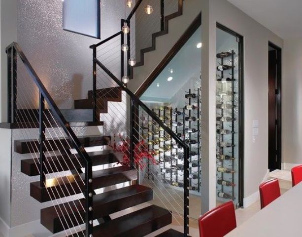 A modern small wine cellar under the stairs with wall mounted metal shelves