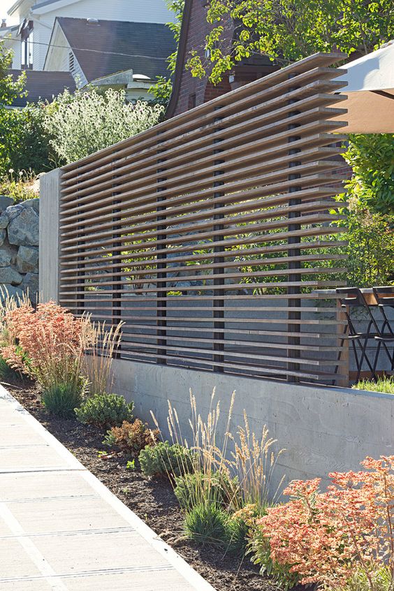 a modern wooden beam privacy screen with a concrete base looks ideal for a contemporary space