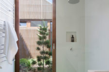 The bathroom features a floor to ceiling window door and a bright green floor in the shower