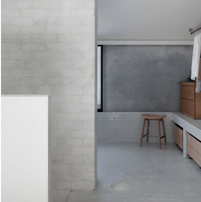 The bathroom shows off how to combine plaster, concrete and brick plus white tiles harmoniously in one space and add wood to it for a warmer look