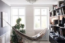06 a gorgeous reading nook with a hammock, a rug, ottomans and a bookshelf that separates the nook from the rest of the space