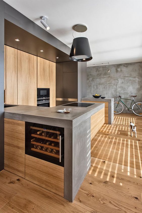 A minimalist industrial kitchen of light colored wood with concrete countertops plus metal touches