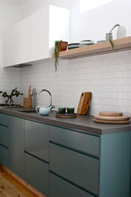 a contemporary teal and white kitchen is spruced up with a cocnrete countertop and a white tile backsplash