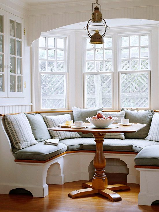 A cozy built in chalf circle banquette seating with a small rustic table look very inviting