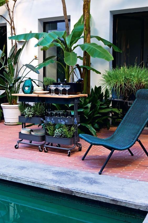 a gorgeous outdoor bar in black with a wooden countertop using two IKEA Raskog carts for storage