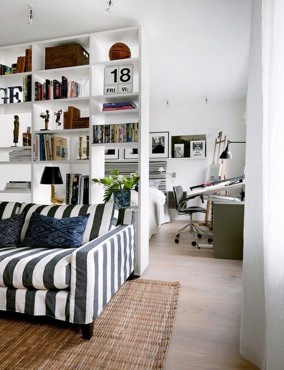 a white shelving unit separates the living room and the bedroom making the latter more private