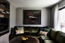 Here’s a TV room with a moody green velvet sofa and a matching artwork