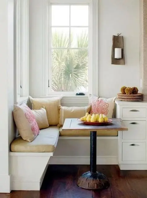 a little breakfast nook with a built-in corner banquette seating and a tiny table