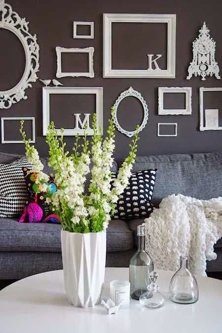 an assortment of various white empty frames works as a gallery wall and spruces up the black wall