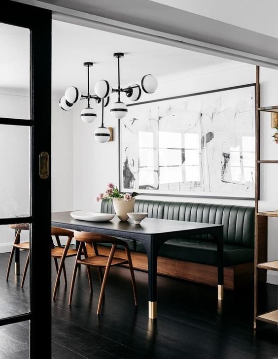 A mid century modern space with a green leather banquette seating and a black table